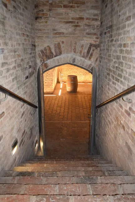 Escalier en briques descendant vers une porte voûtée et un fût éclairé à San Gimignano