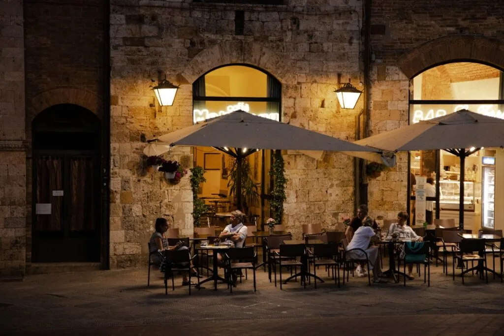 Terrasse éclairée le soir sur une place animée de San Gimignano