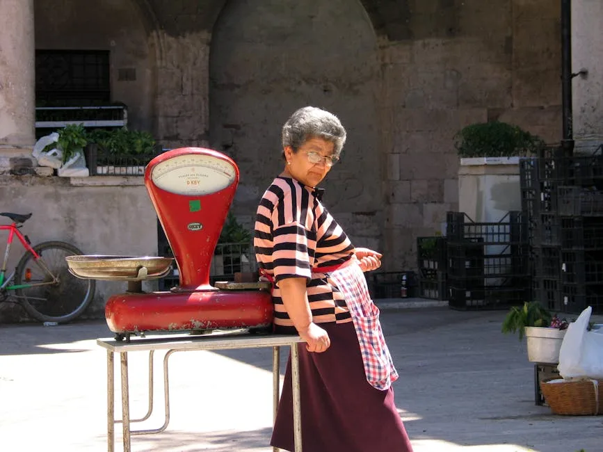 Vendeuse appuyée sur une balance rouge sur une place de San Gimignano