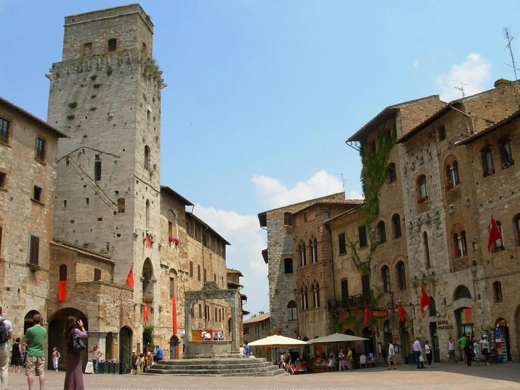 Place pavée de San Gimignano avec tour médiévale et puits central
