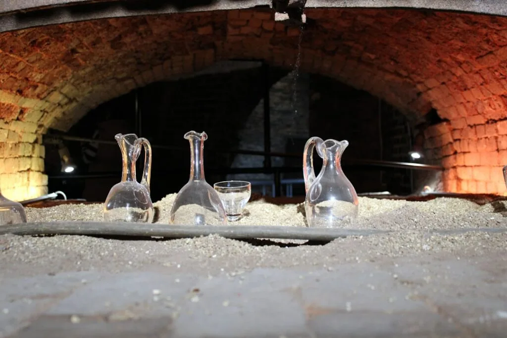 Flacons en verre posés sur sable sous voûte en briques à San Gimignano