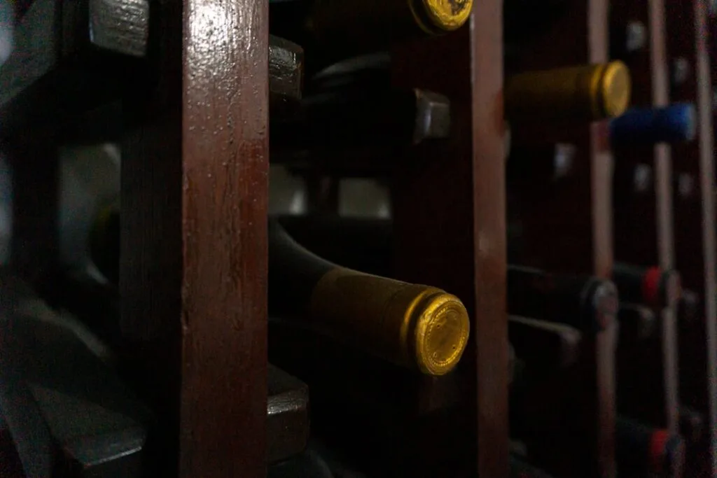 Bouteilles de vin couchées dans une cave de San Gimignano, bouchons dorés visibles