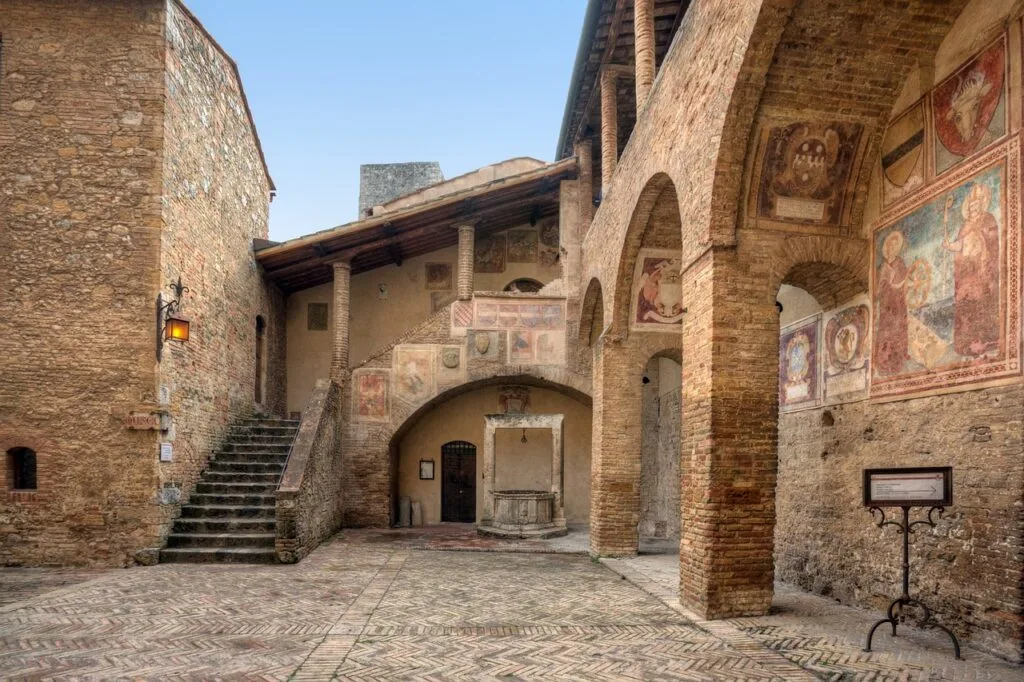 Cour intérieure à San Gimignano avec arches et fresques murales anciennes